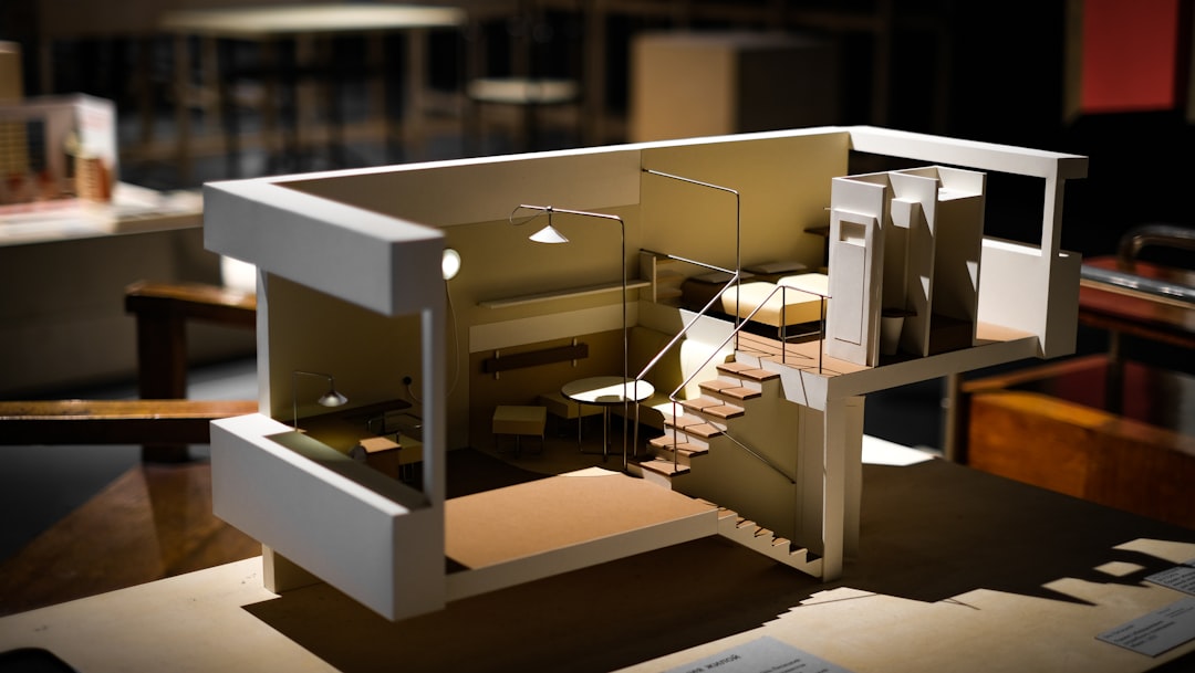 An architectural scale model of a multi-level home, cut away to show its rooms and staircase, displayed on a table.