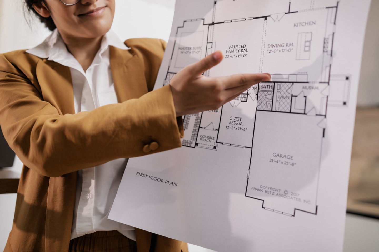 A real estate agent presents a printed home floor plan to prospective buyers at a builder's sales centre.
